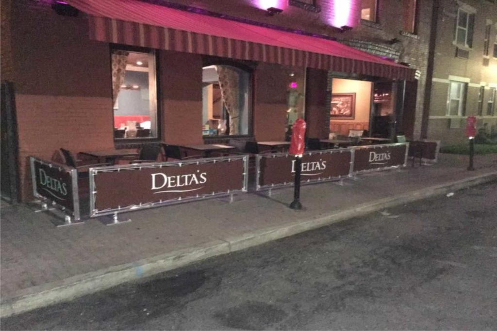Outdoor seating and cafe area with sidewalk partition's at Delta's by New York City Signs & Awnings